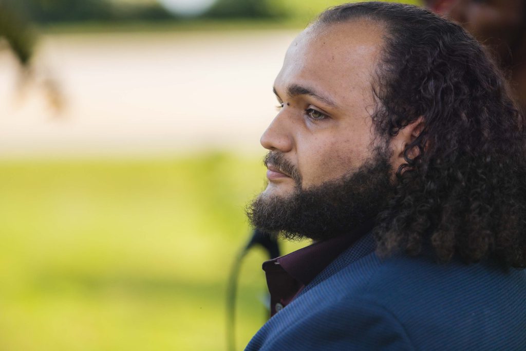 A man with long hair and a beard attending a wedding ceremony.