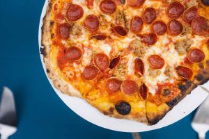 A pepperoni pizza with wedding details on a plate.