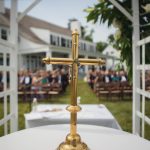 A gold wedding cross amidst a crowd.