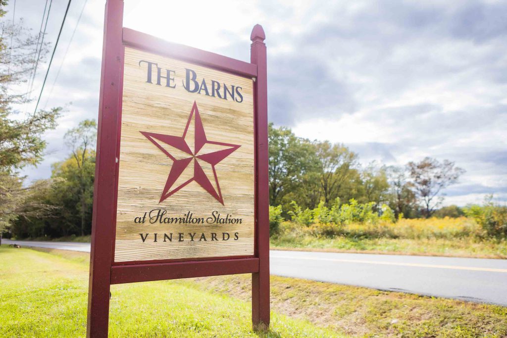 The bard's vineyard sign in front of a country road, featuring wedding details.