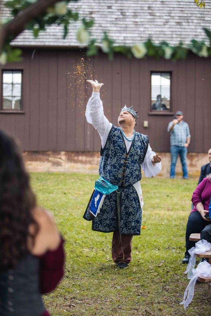 A man in a costume is throwing a frisbee in the air at a wedding ceremony.