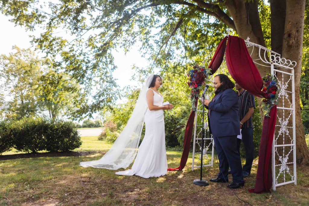 A wedding ceremony with the bride and groom exchanging vows under a tree.