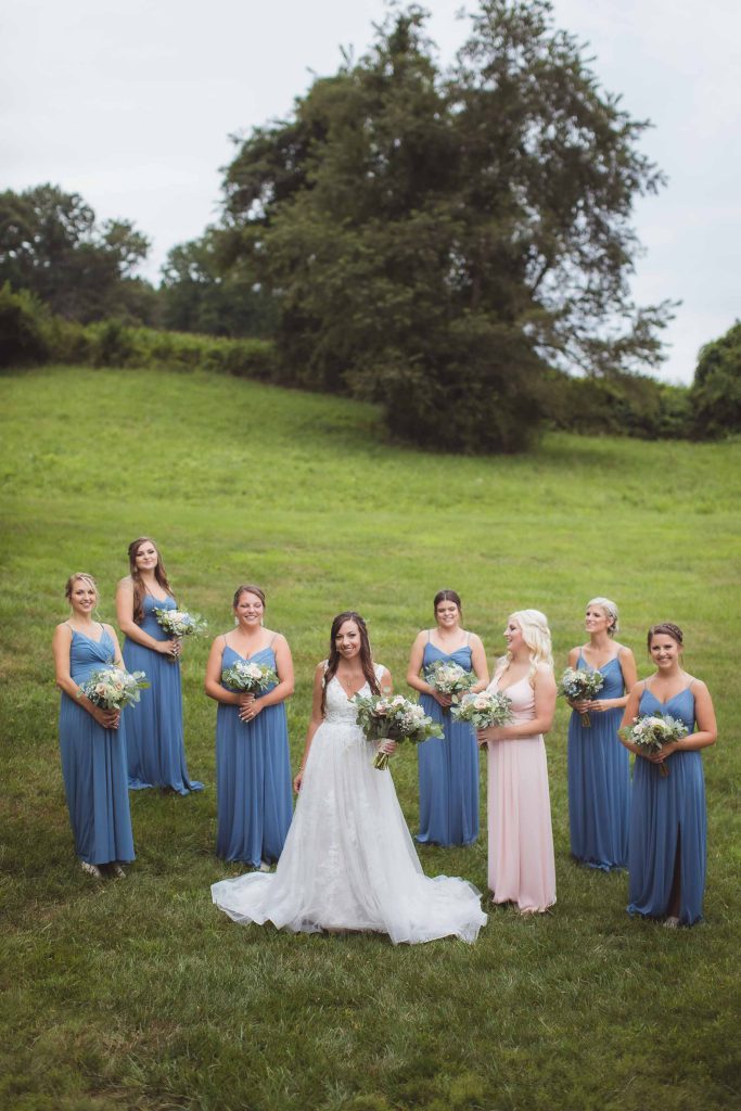A wedding portrait of bridesmaids in blue dresses in a field.