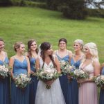 A wedding portrait of bridesmaids in blue dresses in a field.