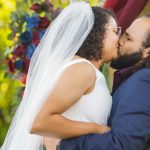 A couple exchanging vows during their wedding ceremony under an arbor.