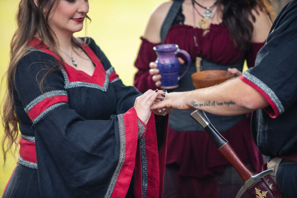 A couple in a costume are holding hands during their wedding ceremony.