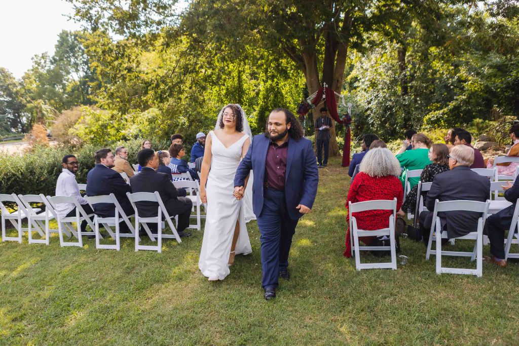 A couple walks down the aisle during their outdoor wedding ceremony.