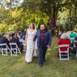 A couple walks down the aisle during their outdoor wedding ceremony.