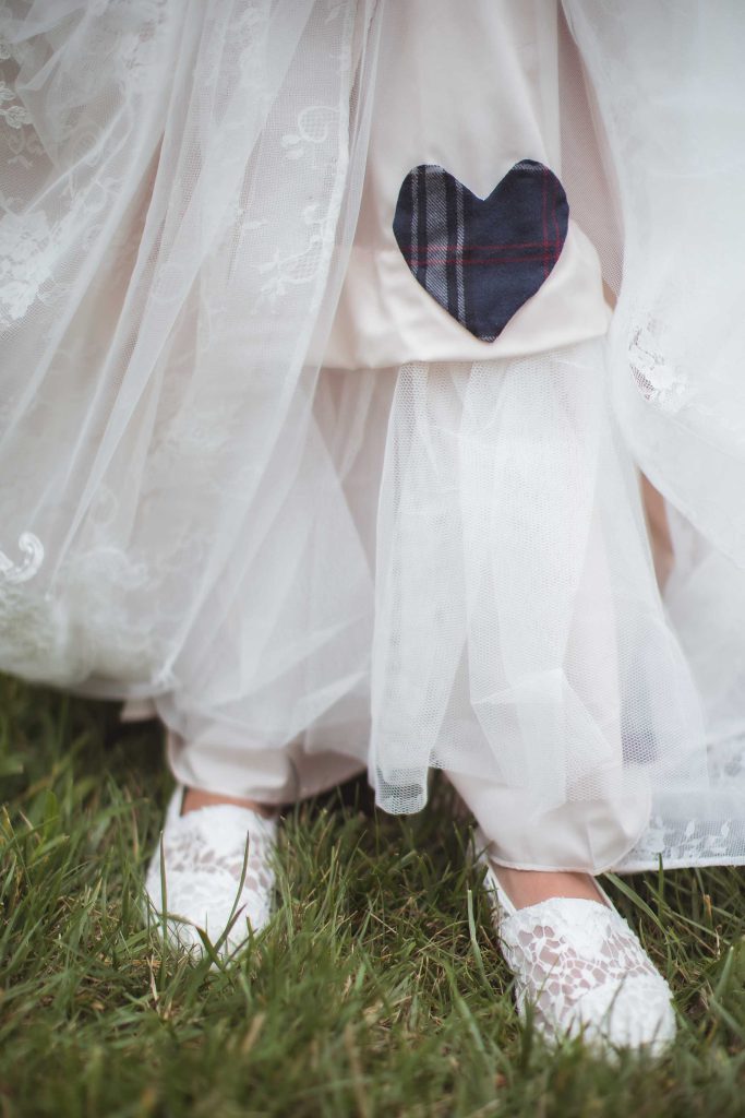 A bride in a white dress with a heart on her shoe.