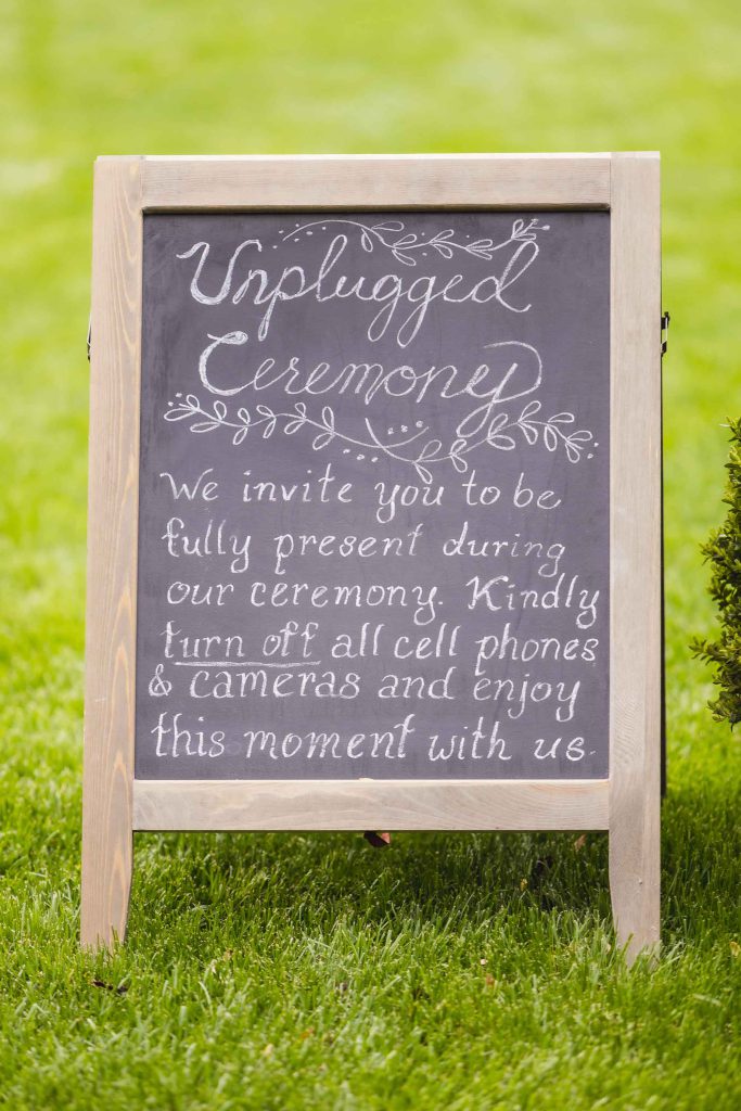 A wedding ceremony sign in the grass.