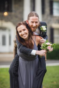 A man is carrying a bride on his shoulders during their wedding.