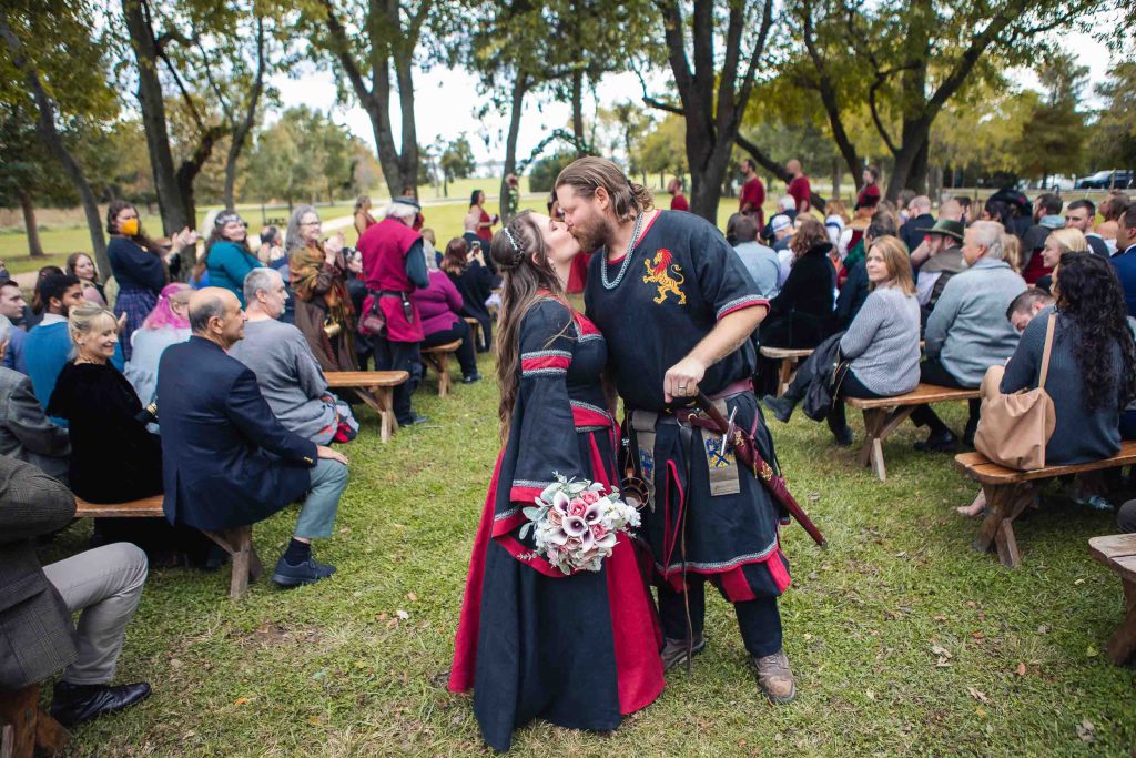A bride and groom share a medieval-themed kiss during their wedding ceremony.