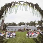 A wedding ceremony at a farm with a large arch.