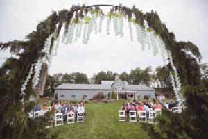 A wedding ceremony at a farm with a large arch.