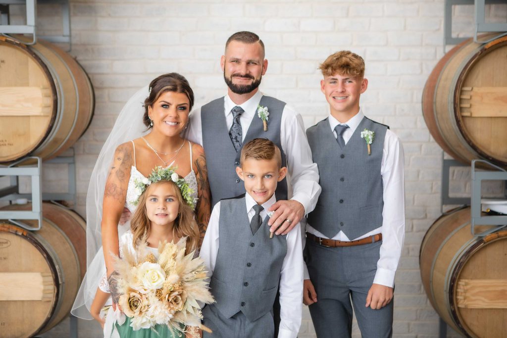 A wedding portrait in front of wine barrels.