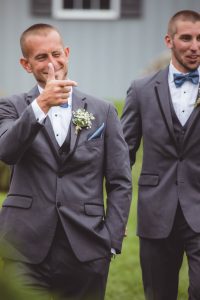 Two groomsmen in tuxedos standing next to each other at a wedding ceremony.