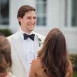 A man in a white tuxedo at a wedding ceremony.