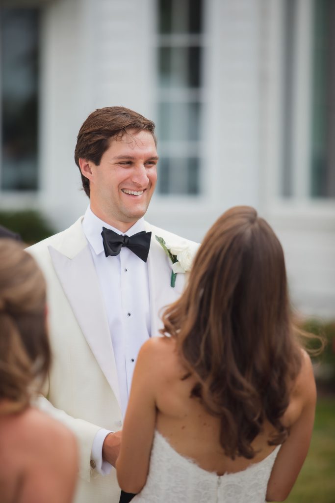 A man in a white tuxedo at a wedding ceremony.