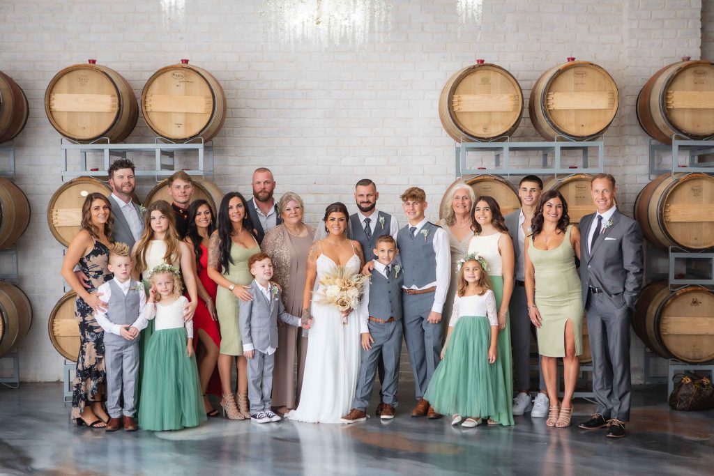 A wedding party posing in front of wine barrels for a portrait.