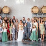 A wedding party posing in front of wine barrels for a portrait.