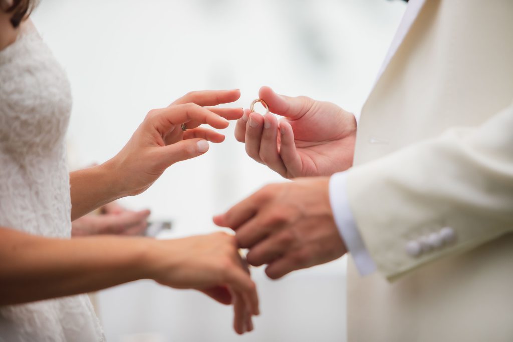 A couple participating in a wedding ceremony exchanging wedding rings.