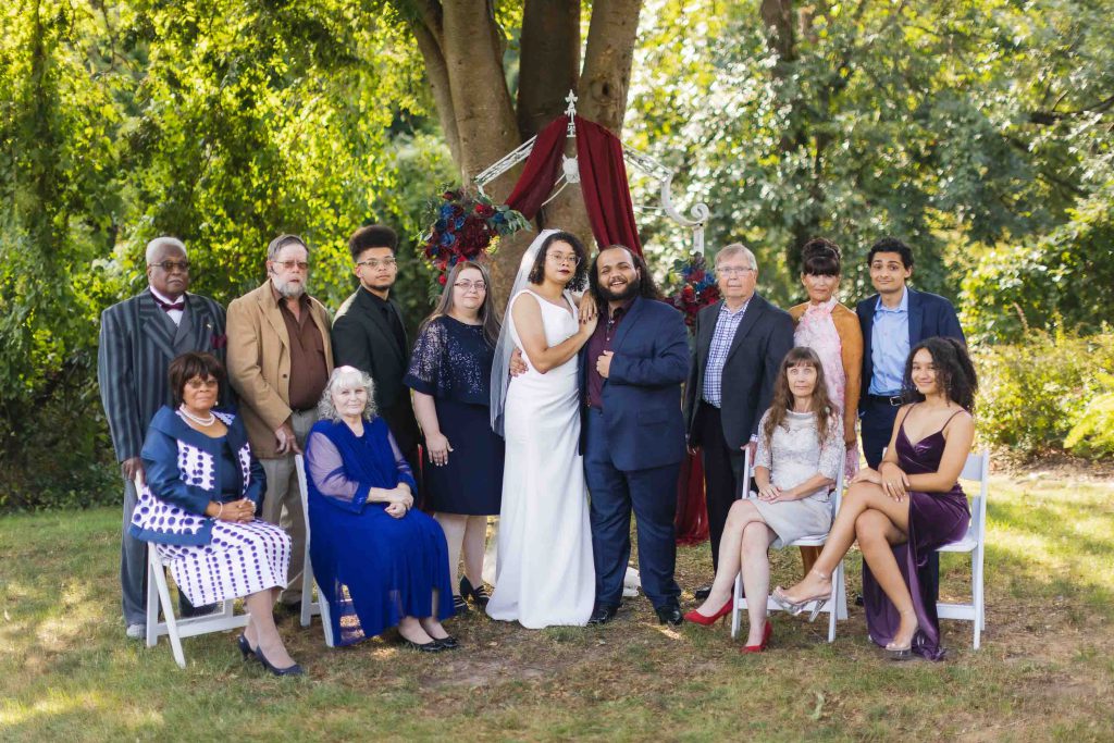 A group of people posing in front of a tree for a wedding portrait.