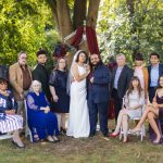 A group of people posing in front of a tree for a wedding portrait.