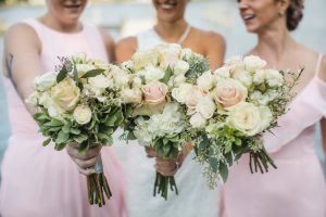 Four bridesmaids holding pink and white bouquets at a wedding.