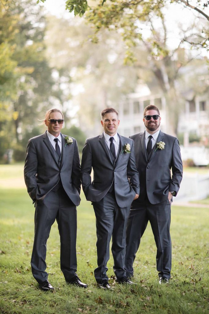 Three groomsmen posing for a wedding portrait.