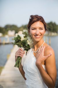 A bride poses for a wedding portrait on a dock with her bouquet.