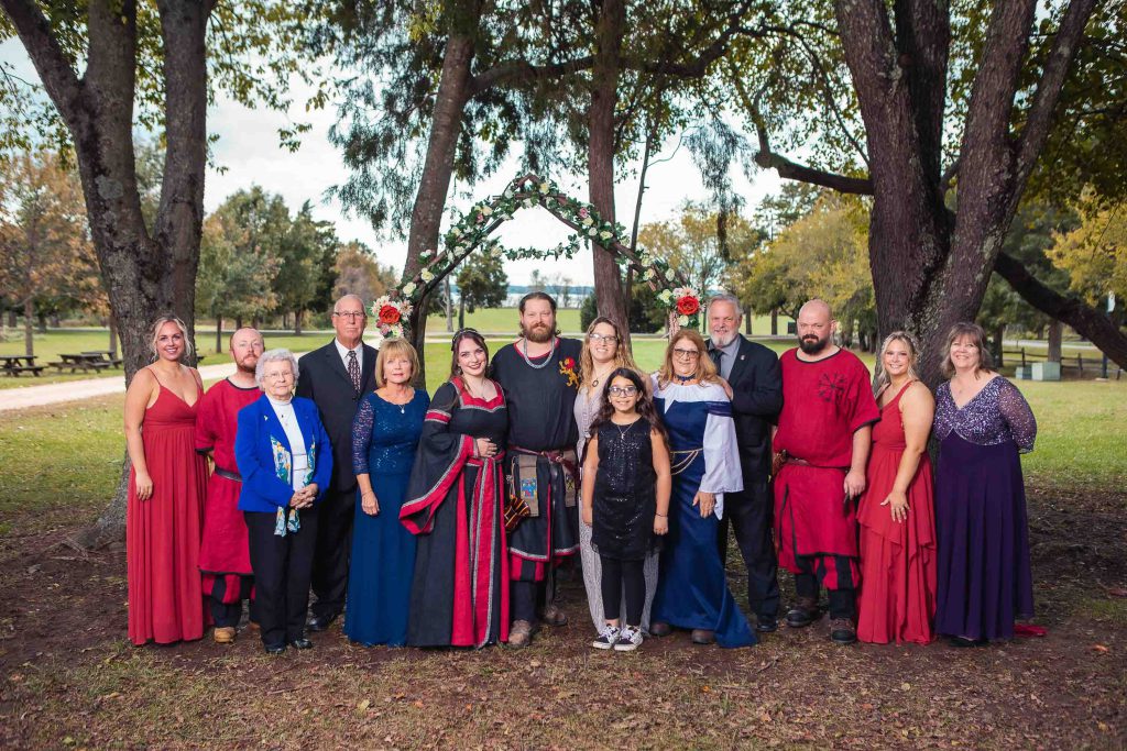 A wedding party posing for a portrait in a park.