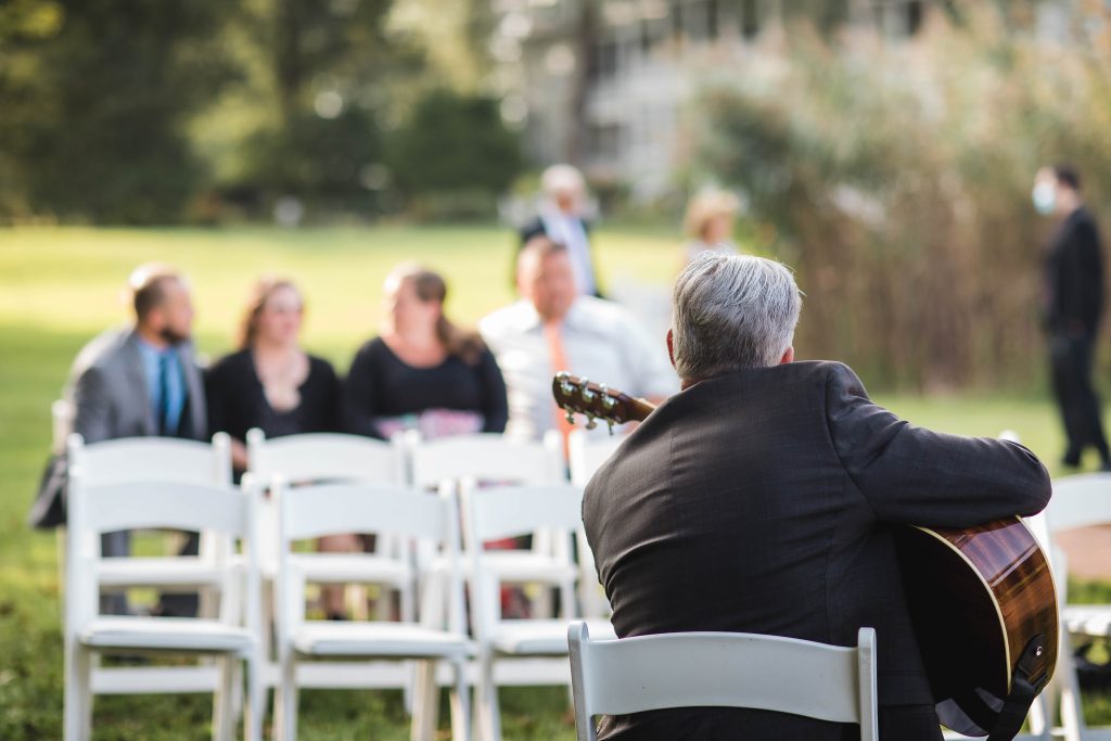 A man performing acoustic guitar music during a wedding ceremony.