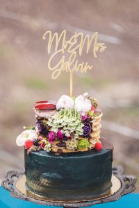 A detailed wedding cake adorned with flowers and a cake topper.