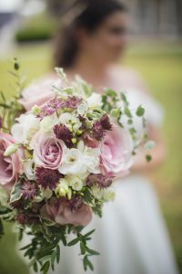 At a wedding, the bride holds a bouquet of pink and white flowers with intricate details.