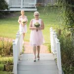 Two bridesmaids walking down a wedding walkway during the ceremony.