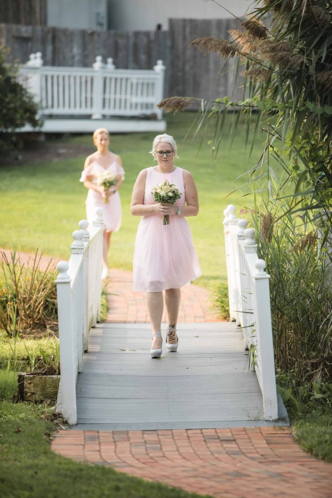 Two bridesmaids walking down a wedding walkway during the ceremony.