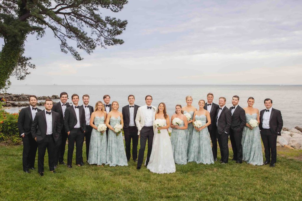 A wedding party standing in front of the ocean.