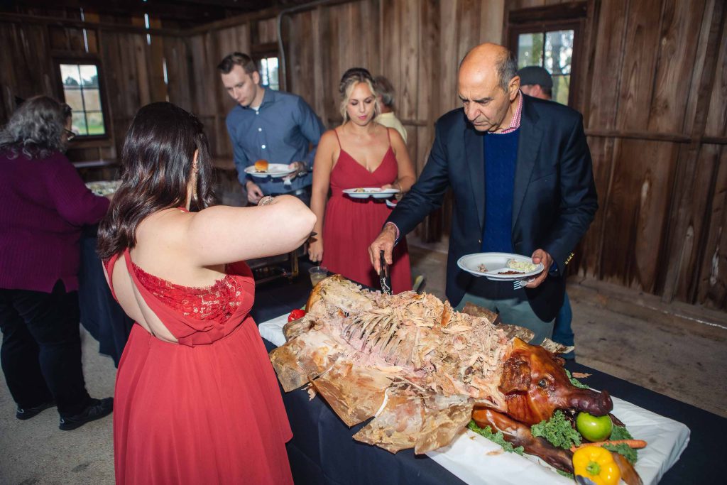 A group of people standing around a wedding reception table with a turkey.
