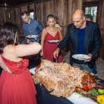 A group of people standing around a wedding reception table with a turkey.