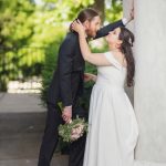 A wedding couple kissing in front of columns.