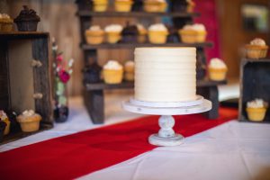 A wedding cake and cupcakes sit on a table together.