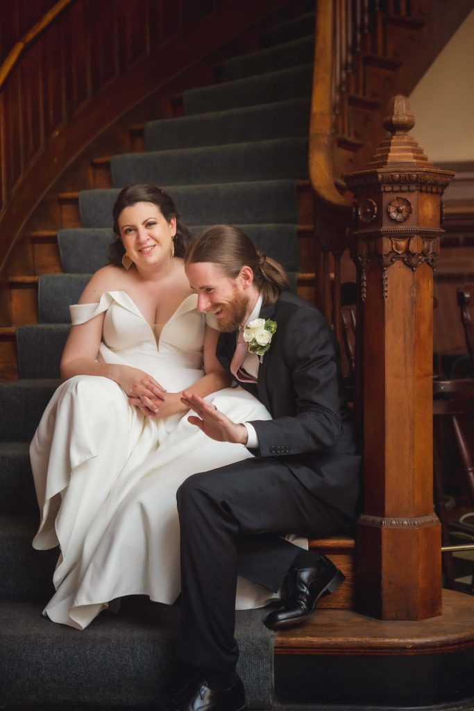 A wedding portrait of a bride and groom sitting on a staircase.