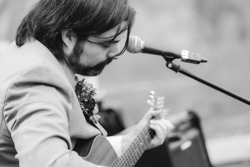 A man playing an acoustic guitar at a wedding reception.