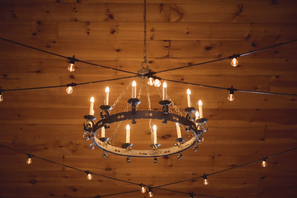 A detailed chandelier hanging from a wooden ceiling at a wedding.