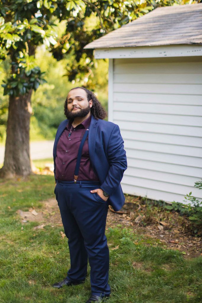 A man in a suit standing in front of a house for a wedding portrait.