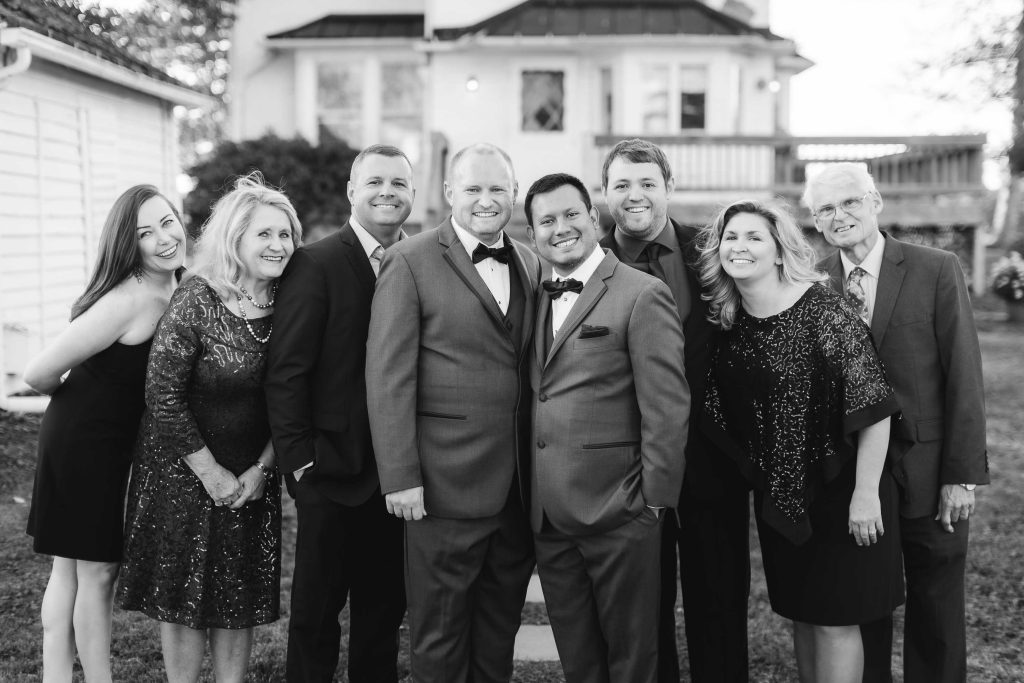 A group of people posing for a wedding portrait in front of a house.