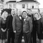 A group of people posing for a wedding portrait in front of a house.