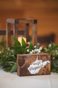 A wooden sign engraved with the words "West Virginia" adds rustic wedding details to the table.