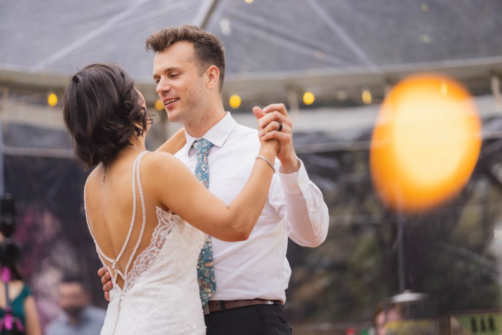 A bride and groom sharing their first dance at their wedding reception in a tent.