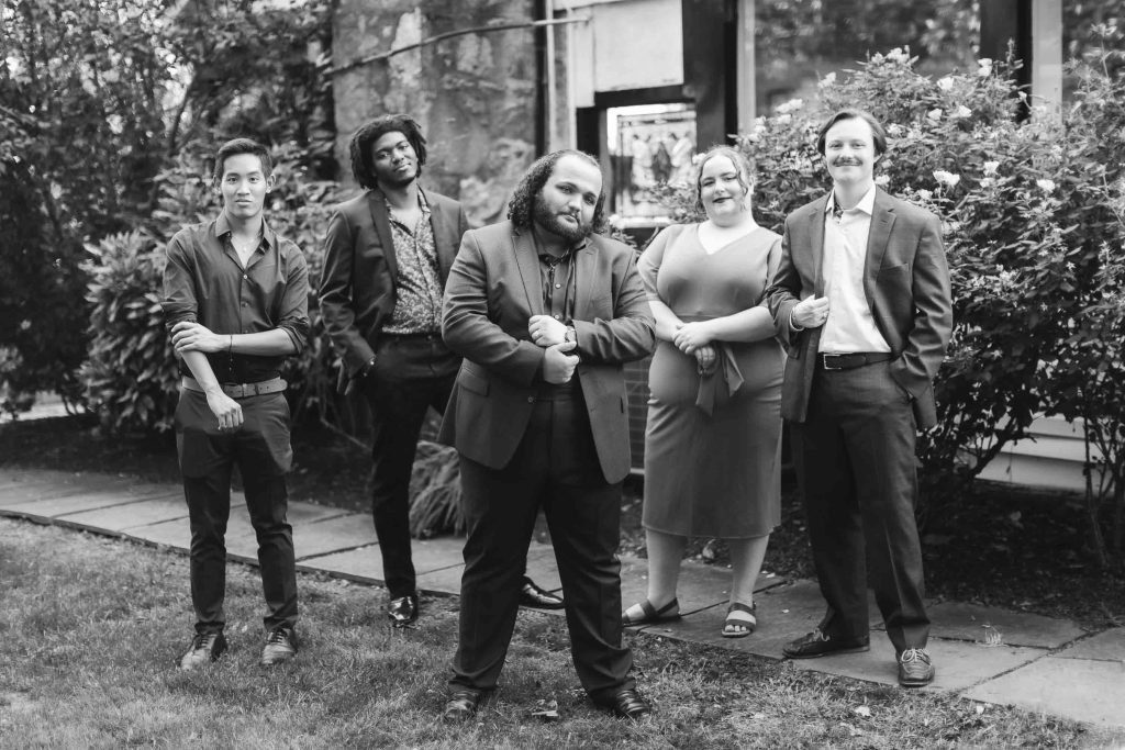A black and white portrait of a group of people posing at a wedding.